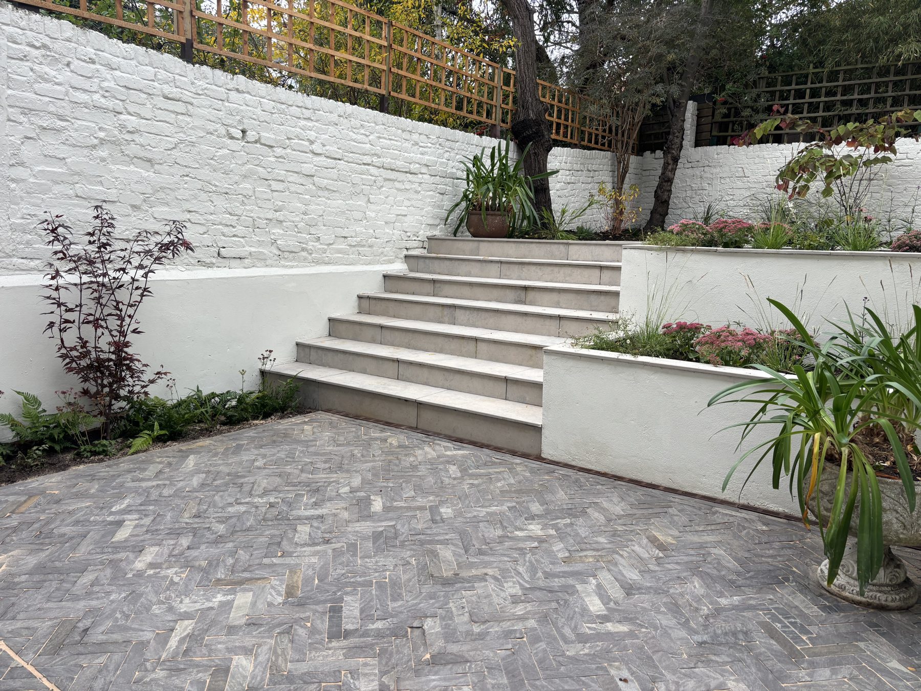 Stone steps and herringbone paving in a shady walled Brixton garden